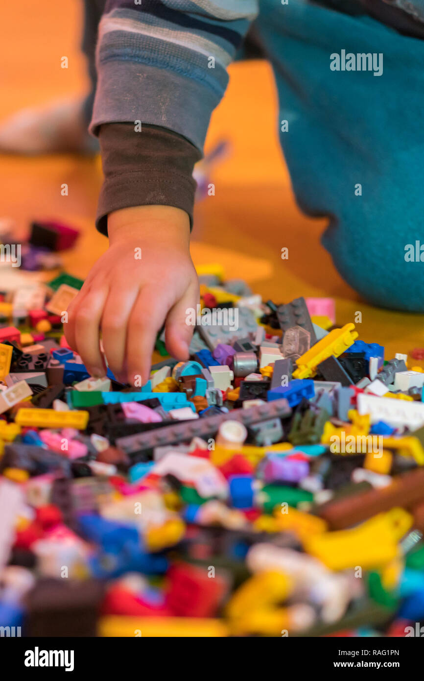 Close up of colorful plastic bricks on the floor. Early learning. Children's plastic constructor on the floor. Children's hands play a little construc Stock Photo
