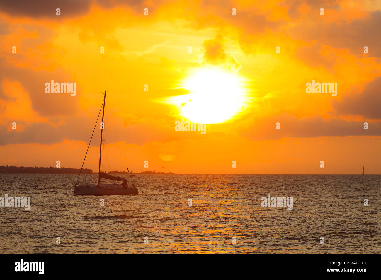 Dramatic orange sunset over the sea with a yacht Stock Photo - Alamy