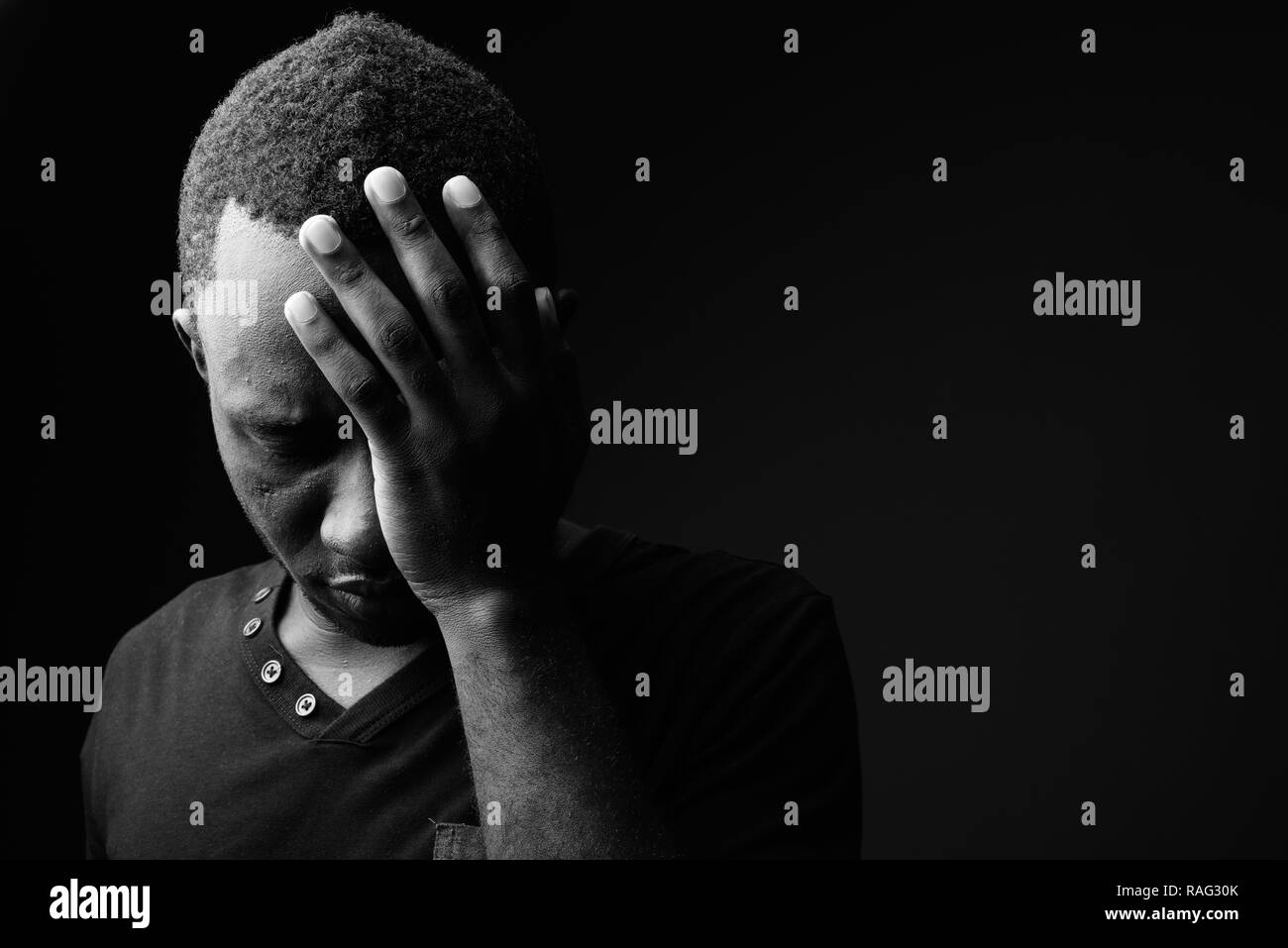 Sad young African man looking stressed in black and white Stock Photo