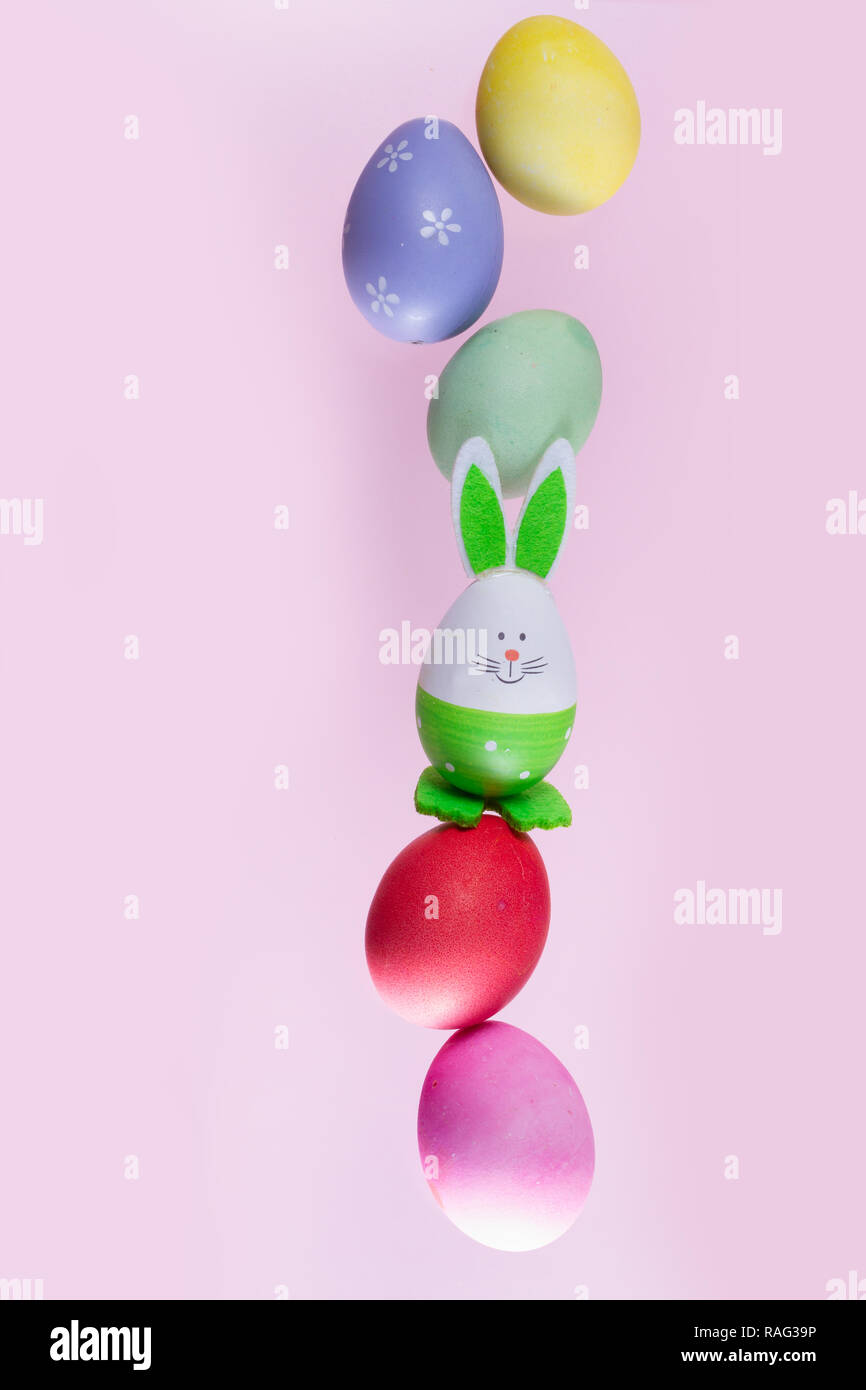 falling funny easter bunnies and colored easter eggs on pink background Stock Photo