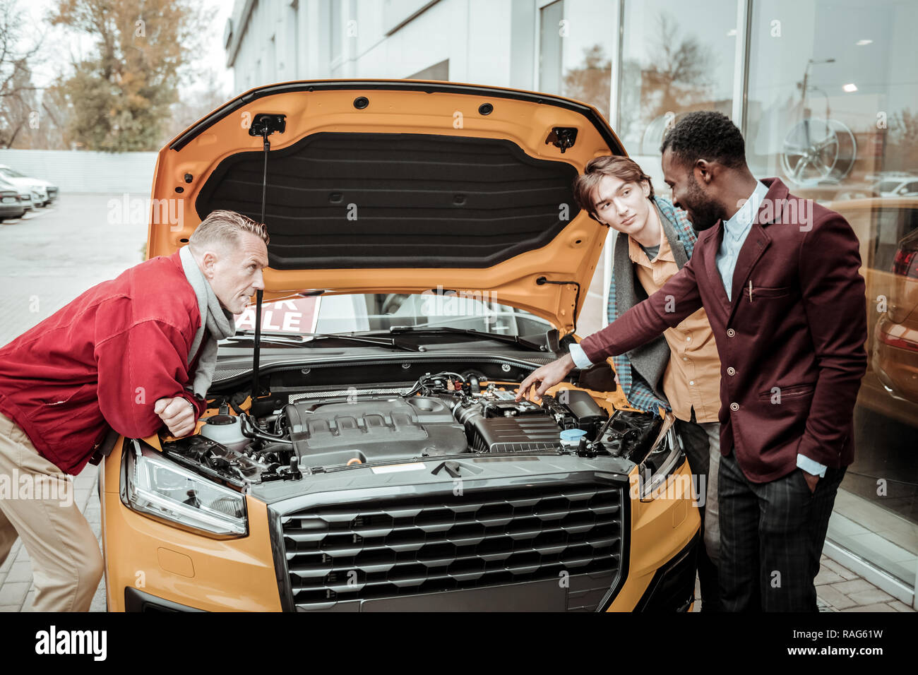 AfricanAmerican car sales consultant telling about orange car Stock