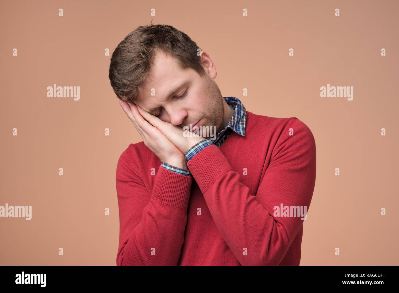 European man in red sweaer being tired standing over brown background. Stock Photo