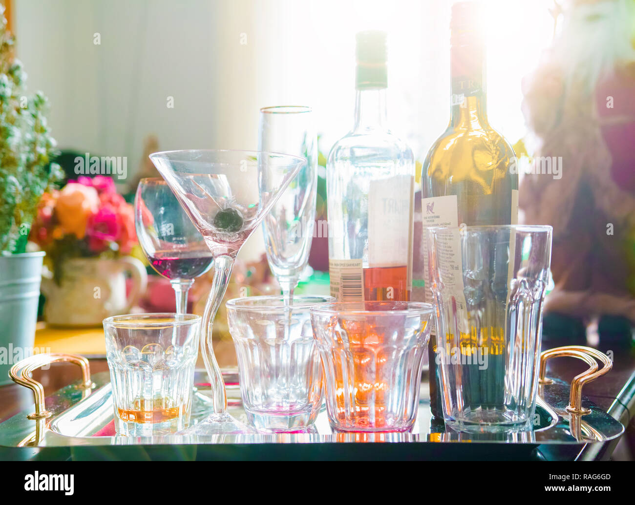 Empty alcohol glasses and two bottles on a tray. Early morning, end of Christmas party. Stock Photo