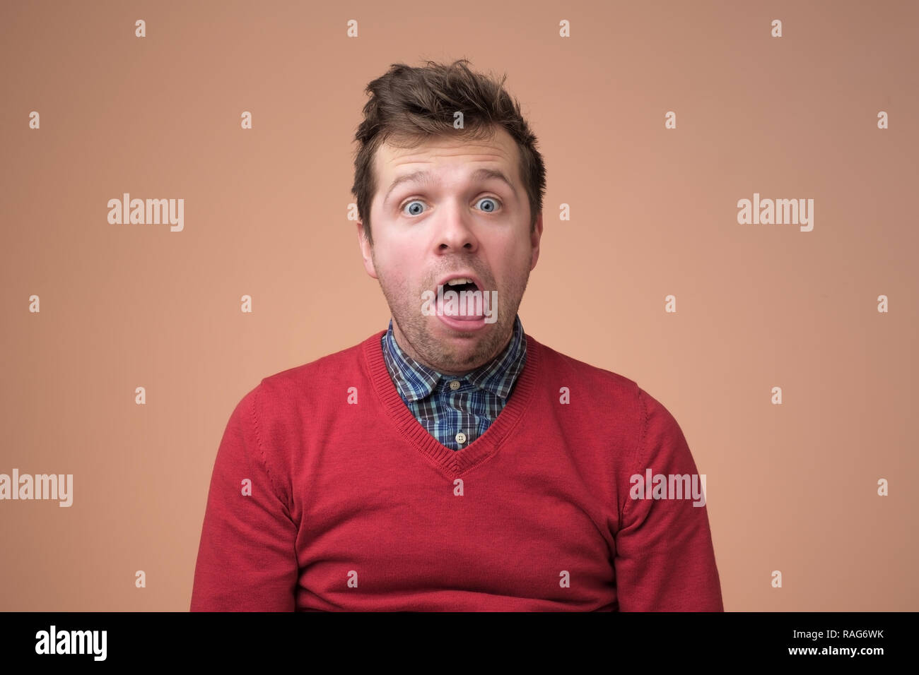 Young funny man in white shirt, gesturing shocked or surprised expression with mouth open Stock Photo