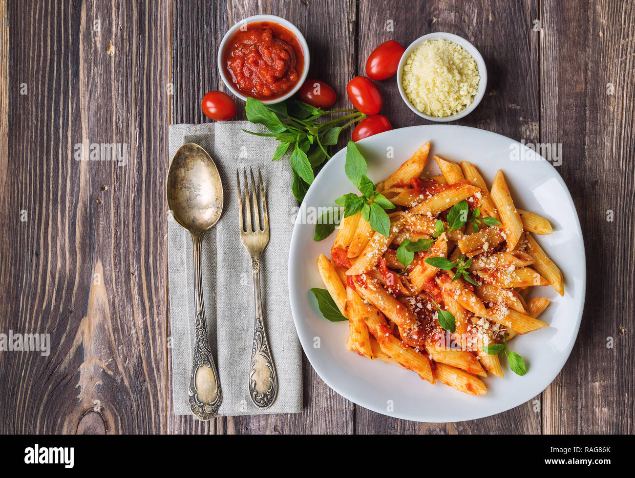 Penne pasta in tomato sauce with basil parmesan cheese on rustic wooden