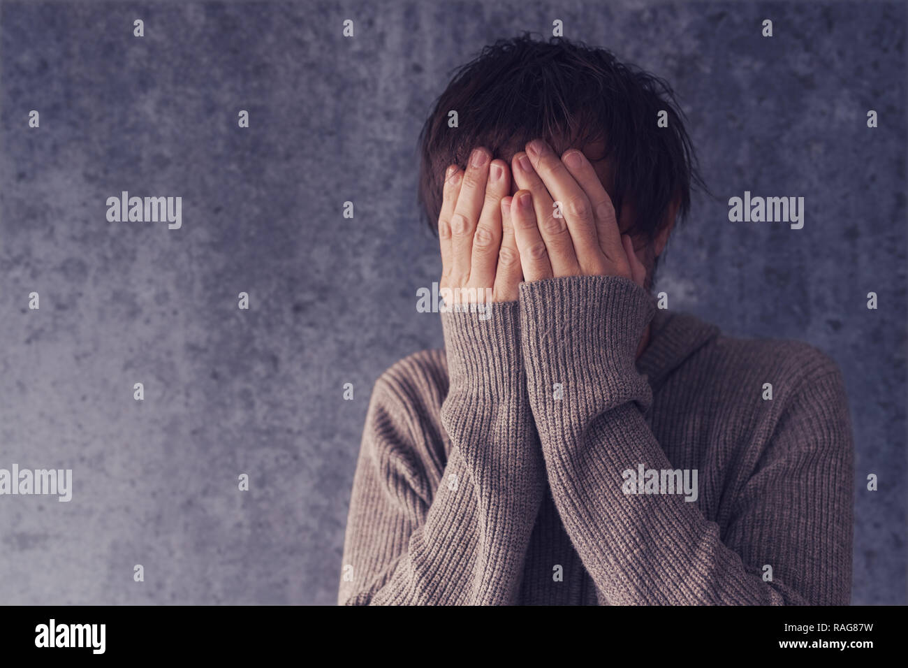 Crying man with face in hands, distraught and sad Stock Photo
