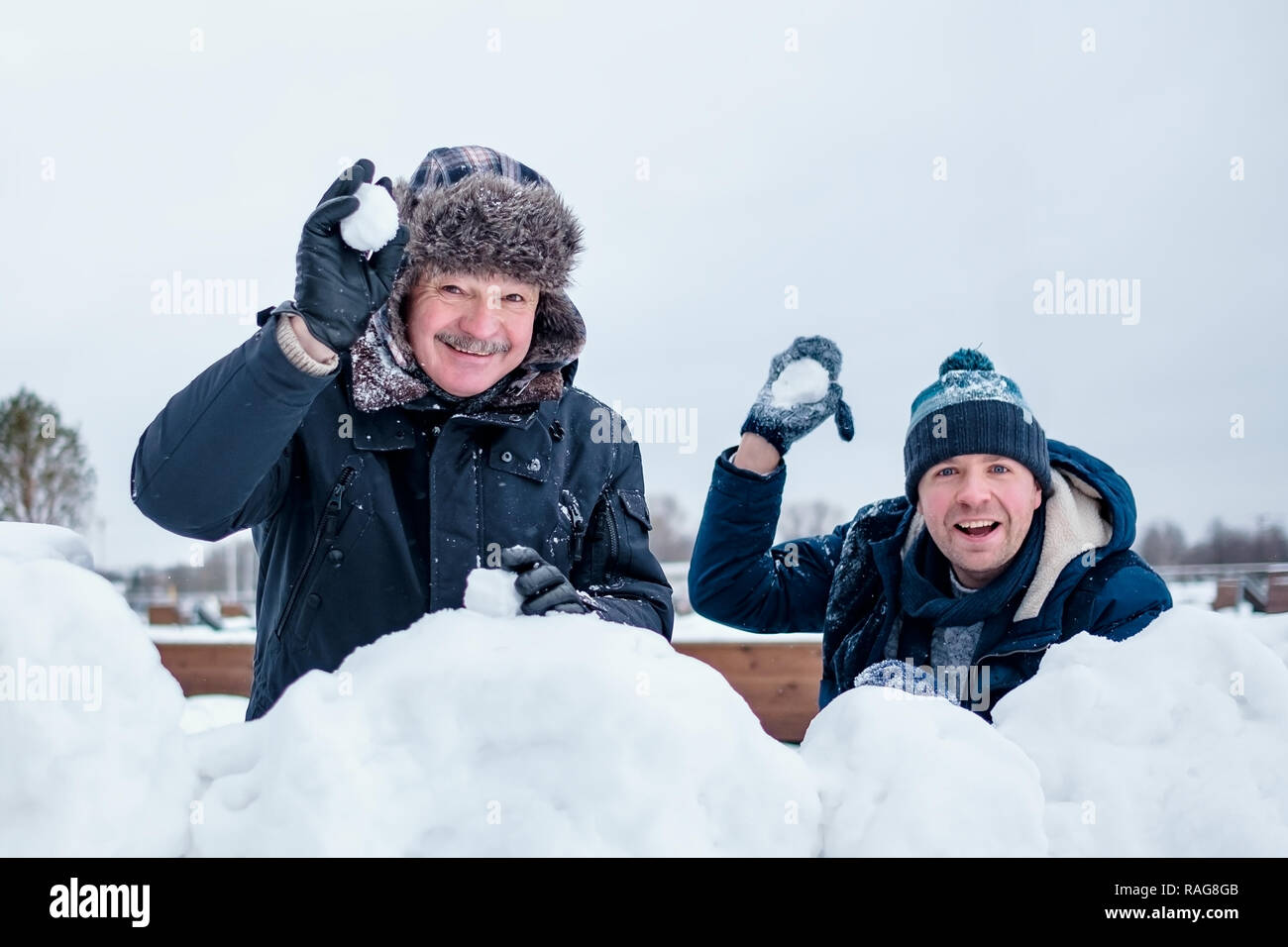 A senior man and his young son throwing a snowball, Stock Photo