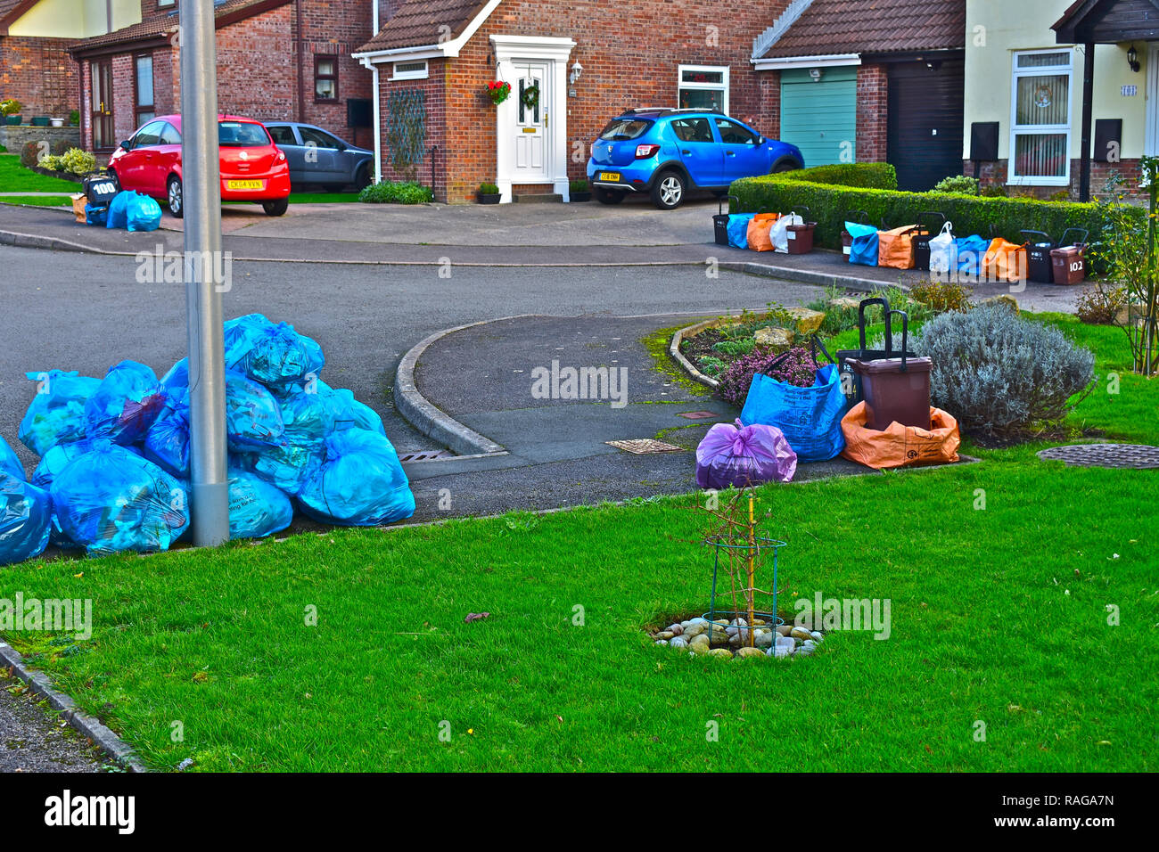 Recycling bags, bins and rubbish piled in street waiting for collection in modern neighbourhood of suburban homes. Stock Photo