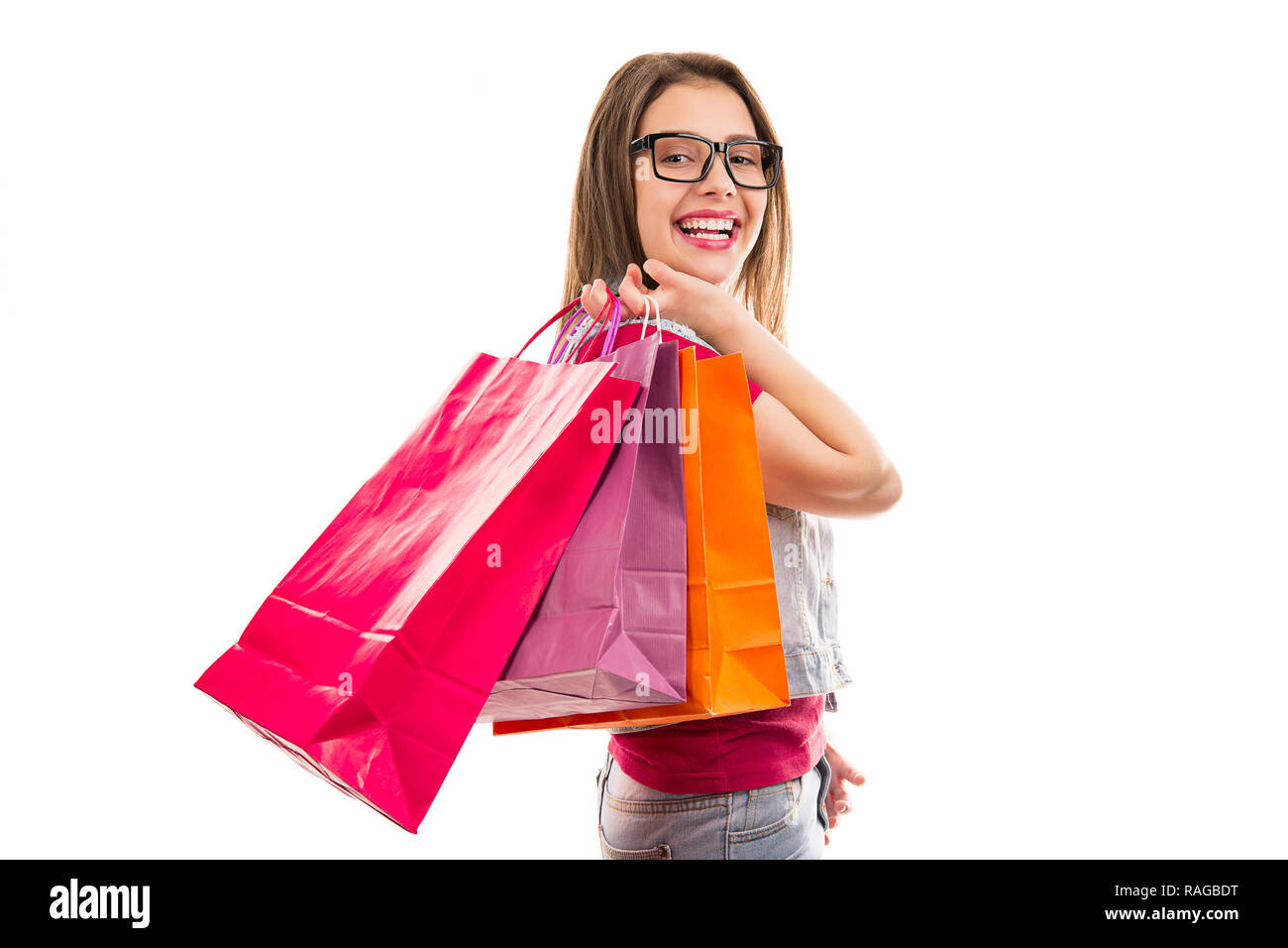 Side view of pretty young woman in glasses holding colorful bags with ...