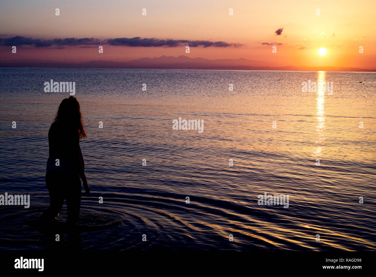 Woman playing with the sun on the beach in greece. Stock Photo