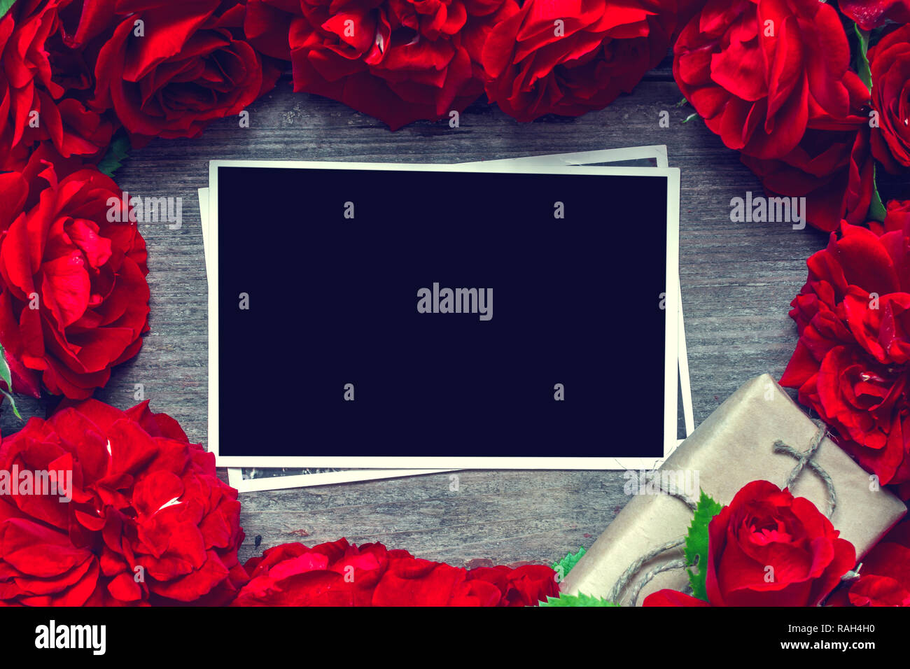 blank photo card in frame made of red roses flowers and gift box. mock up. flat lay. top view. valentines day background. vintage toning Stock Photo