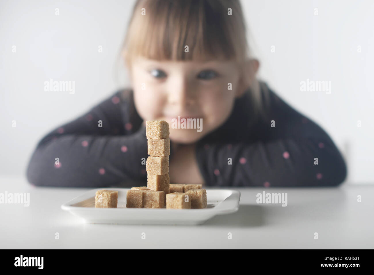 Child, sugar cubes. The problem of excessive consumption of sugar by children under the age of 10 years. Stock Photo