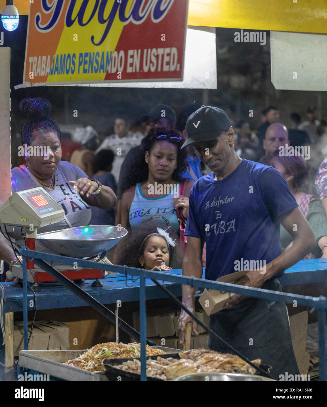 Food vendor dispensing food as little girl looks on, Havana, Cuba Stock Photo