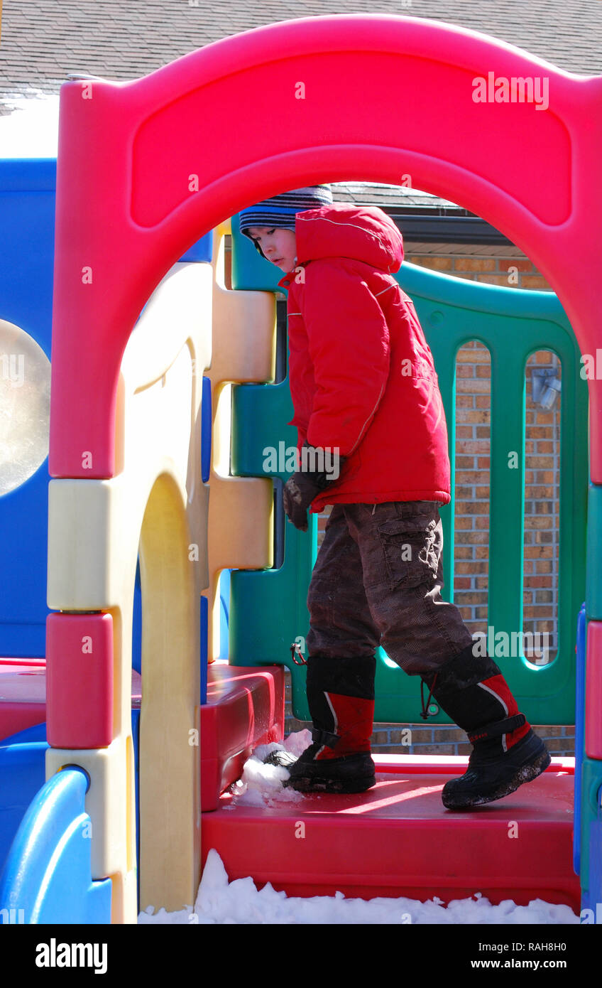 boy plays on child play ground equipment. below freezing day Stock Photo