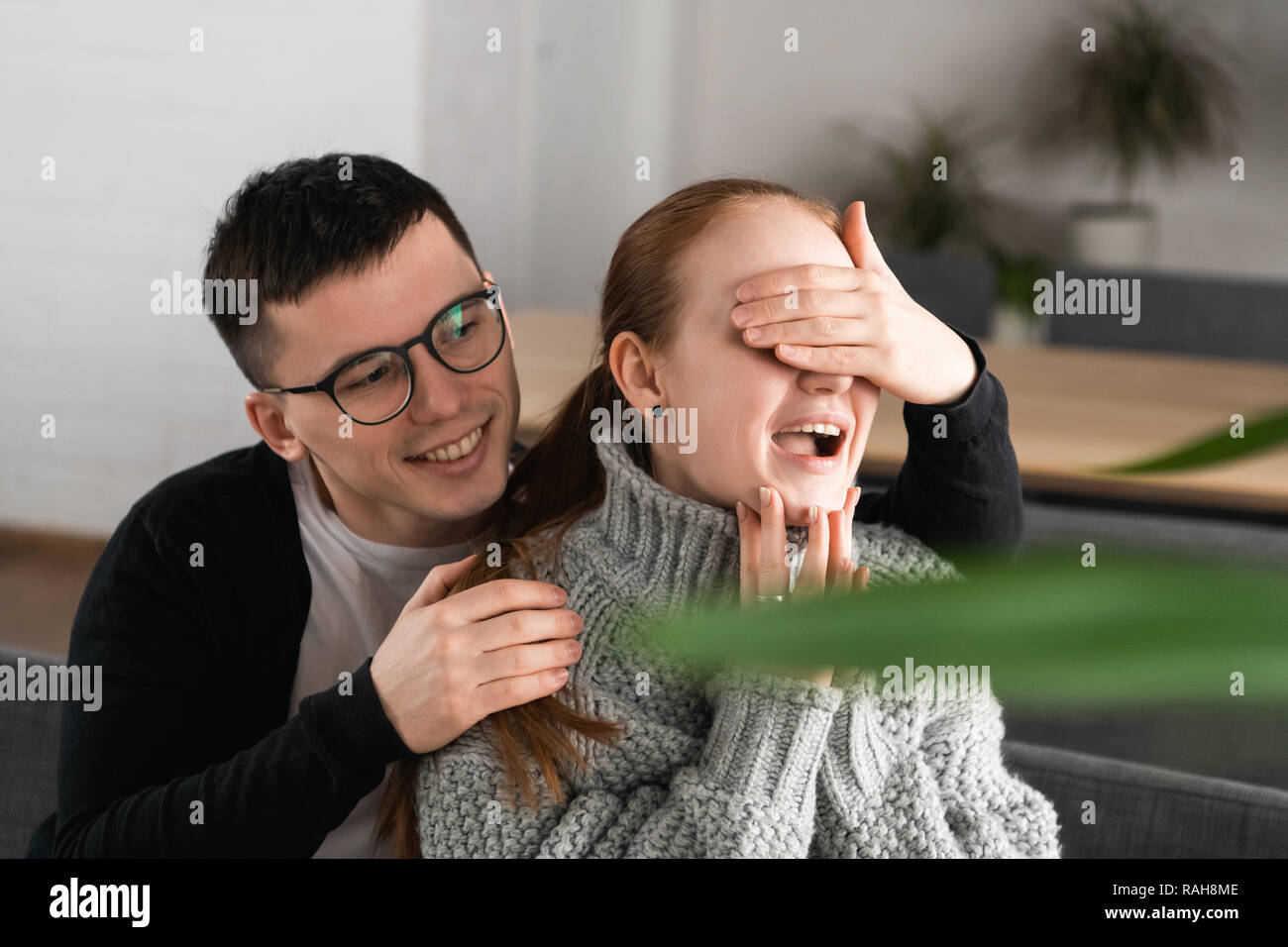Surprise Beautiful romantic couple in cafe. Man is covering his girlfriend's eyes while she waiting for a surprise Stock Photo