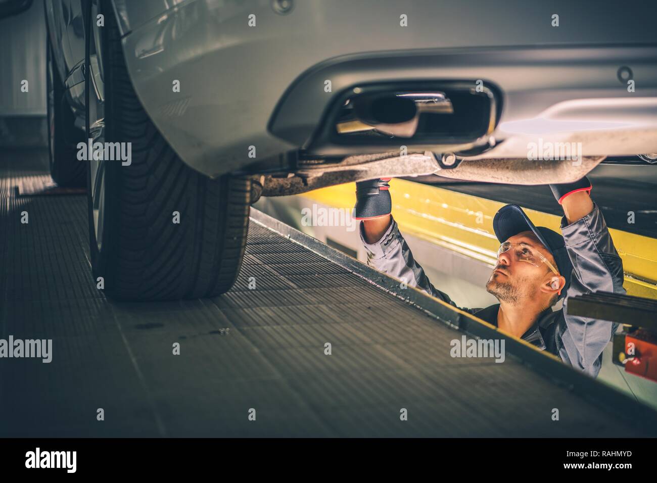 Car Diagnostic Technician Under the Vehicle. Automotive Industry Stock