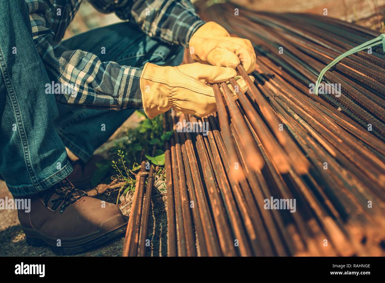 Construction Industry. Steel Reinforcement Bars on a Ground. Contractors Hands on the Steel Elements. Stock Photo