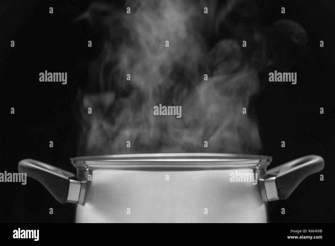 steam over cooking pot in kitchen on dark background Stock Photo