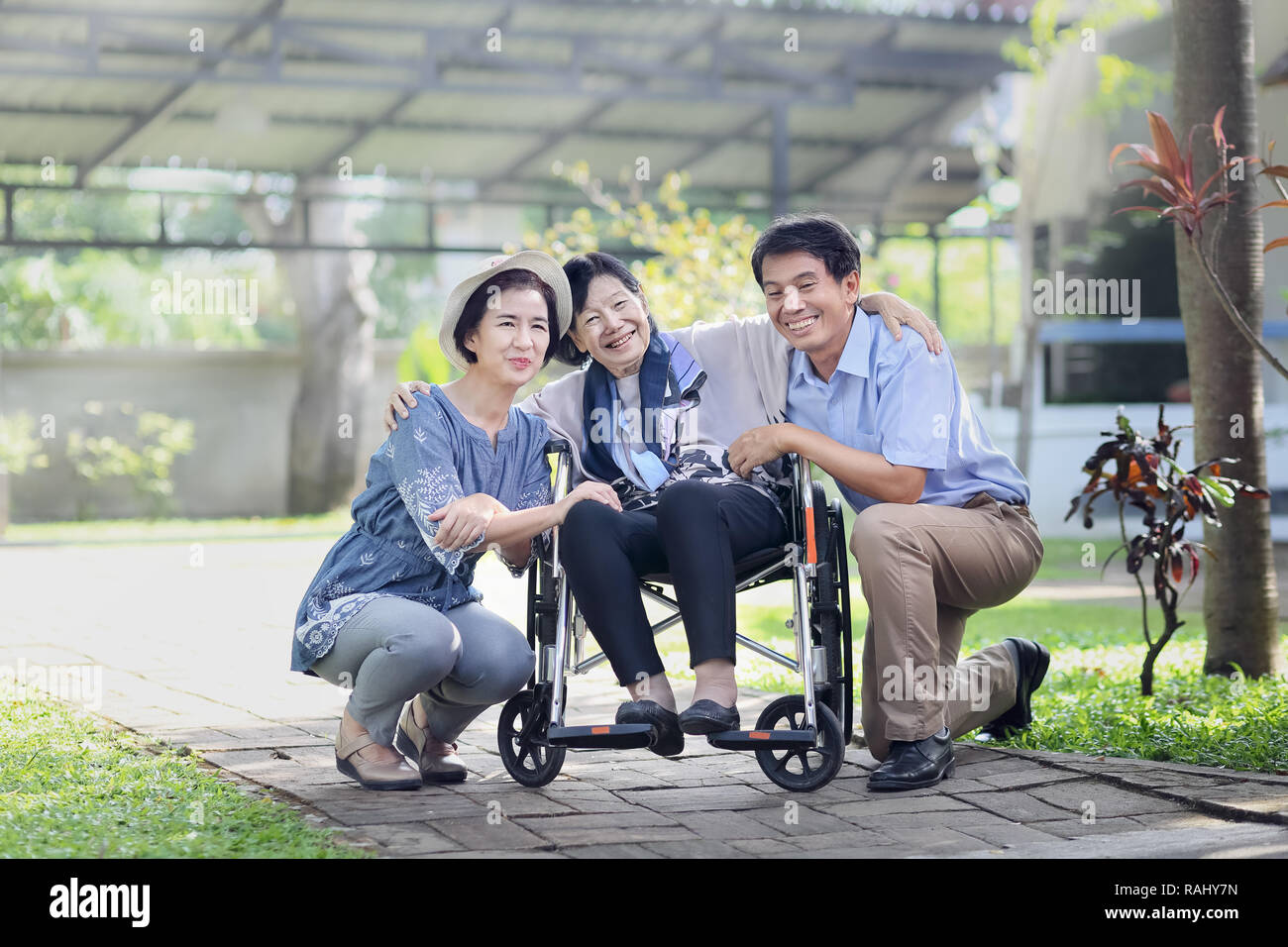 Son and daughter in law looking after elderly mother in backyard Stock Photo