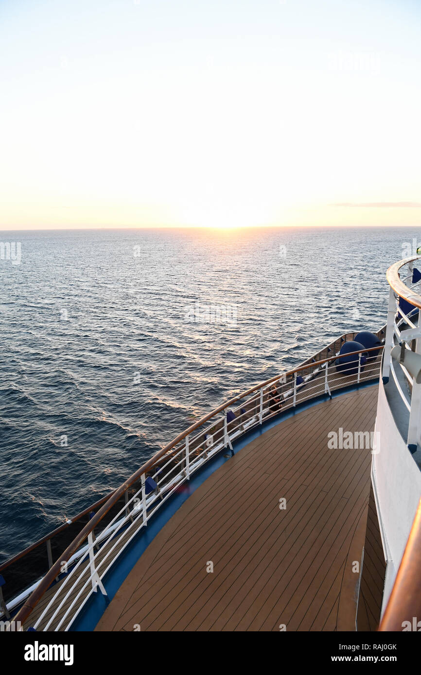 Railing and deck flooring of a cruise ship at sunset with the ocean in ...