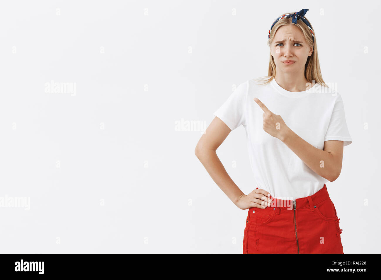 Portrait of displeased intense and worried fair-haired stylish female complaining on something nasty she dislikes, pointing at upper left corner where spider hangs, frowning and grimacing Stock Photo