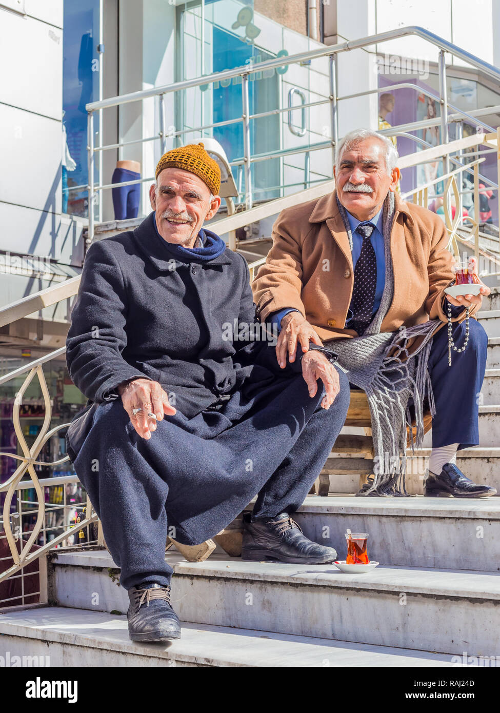 Istanbul, Turkey, February 24, 2015: Two elderly Turkish men seated on some steps, drinking Turkish tea. Stock Photo