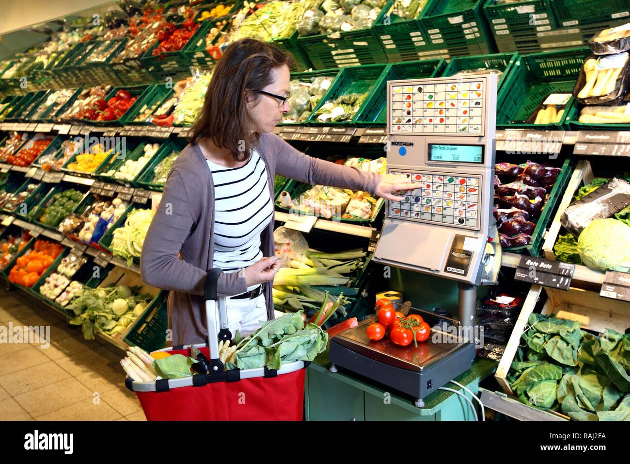 Woman weighing vegetables in the fruit and vegetable section of a self-service grocery department, supermarket Stock Photo