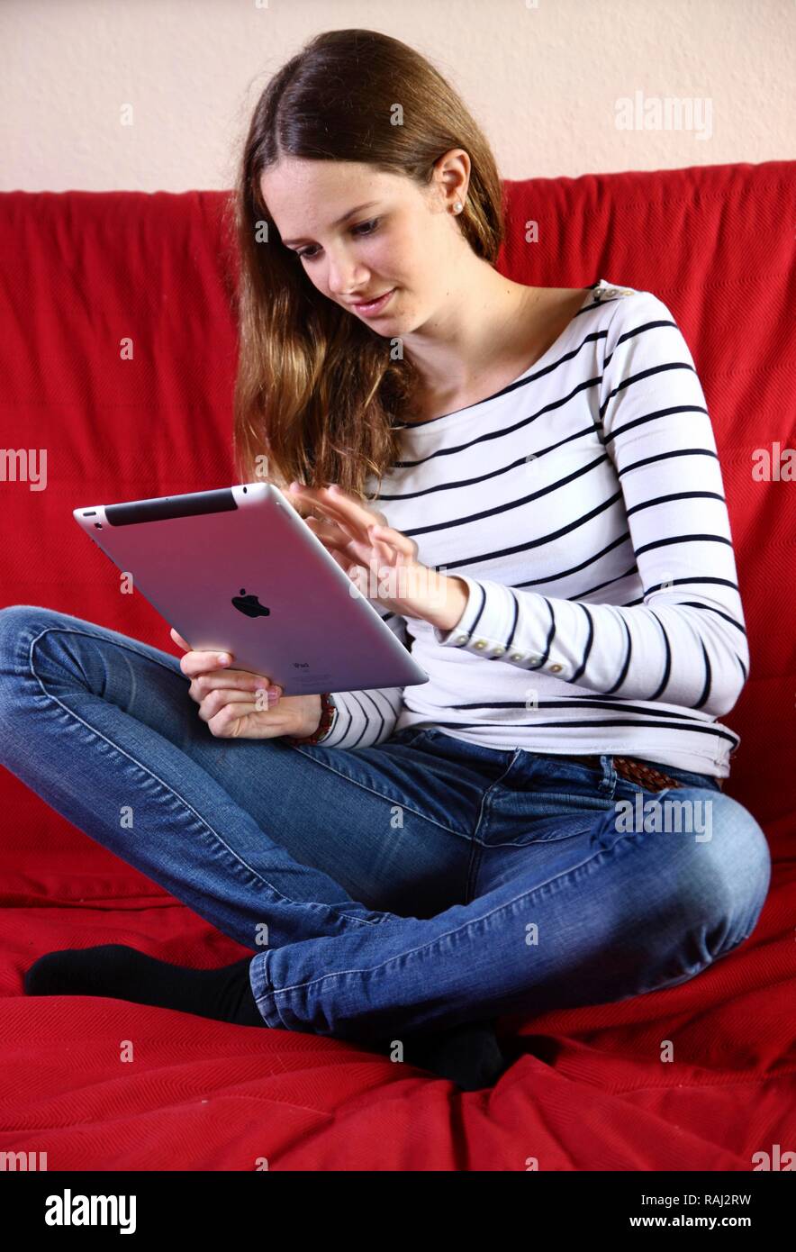 Girl playing at home with an iPad, tablet computer, wireless internet access Stock Photo