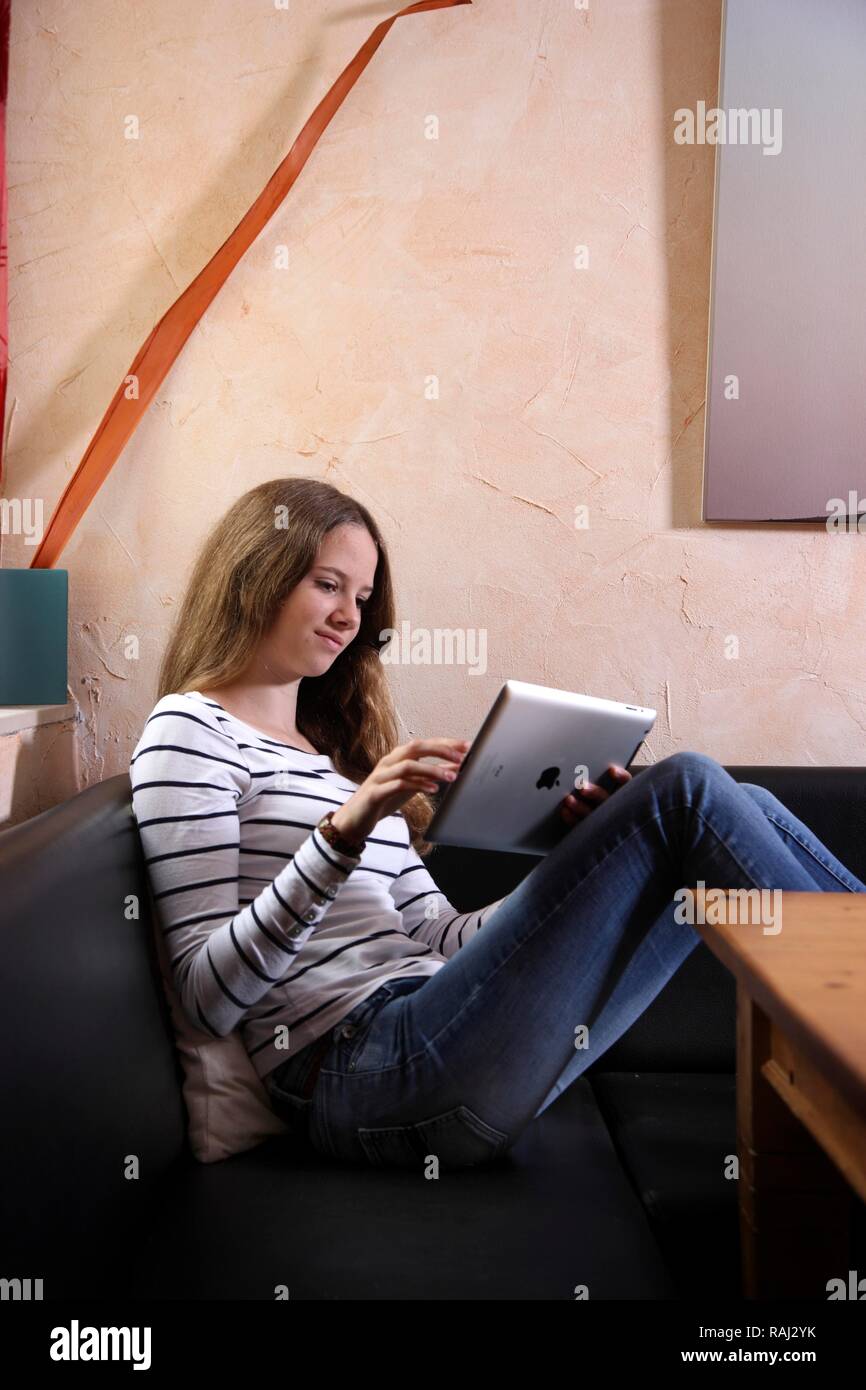 Girl playing at home with an iPad, tablet computer, wireless internet access Stock Photo