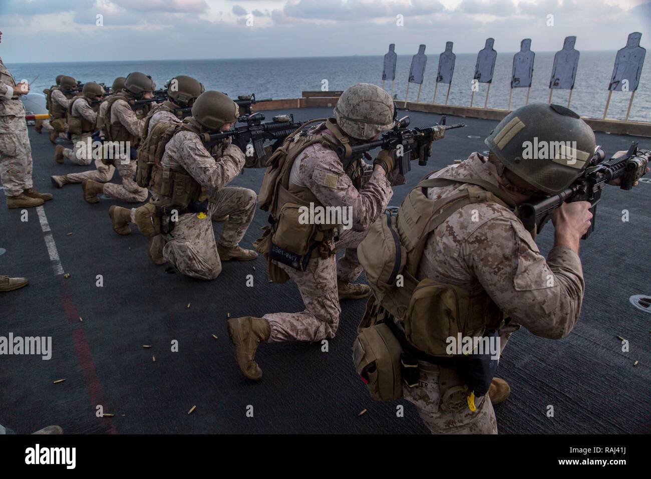 ARABIAN SEA – U.S. Marines with the Command Element, 13th Marine Expeditionary Unit (MEU), fire from the kneeling position during a morning rifle range aboard the Wasp-class amphibious assault ship USS Essex (LHD 2), Jan. 2, 2019. The Essex is the flagship for the Essex Amphibious Ready Group and, with the embarked 13th MEU, is deployed to the U.S. 5th Fleet area of operations in support of naval operations to ensure maritime stability in the Central Region, connecting the Mediterranean and the Pacific through the western Indian Ocean and three strategic choke points. (U.S. Marine Corps photo  Stock Photo