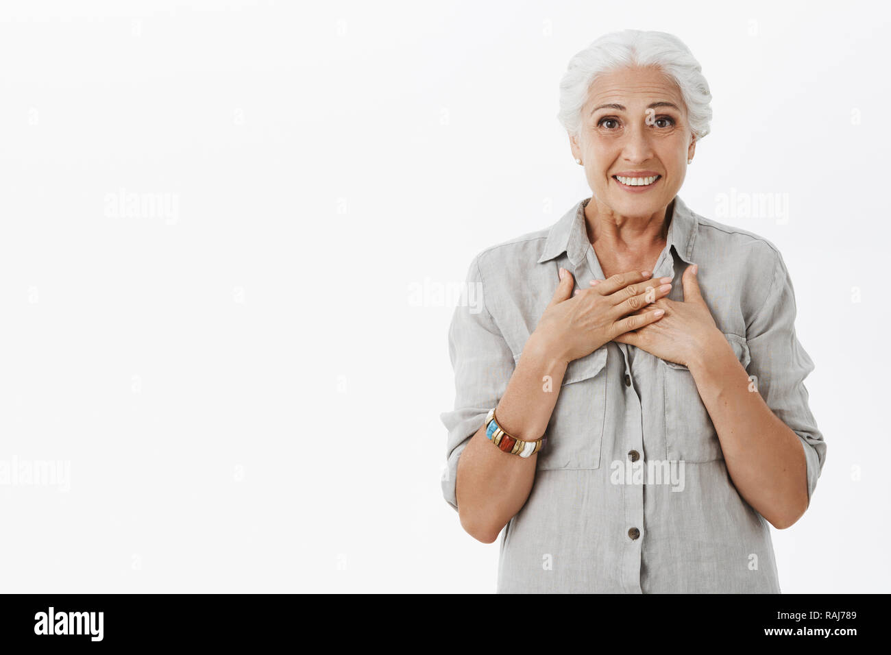 Touched kind and happy elderly mother with grey hair in casual shirt