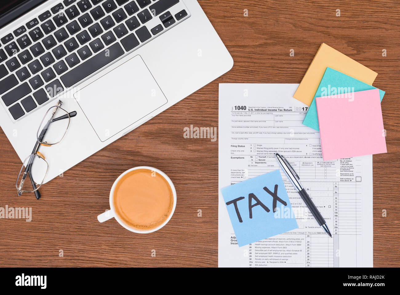 top view of tax form, coffee, laptop and blue card with 'tax' word on