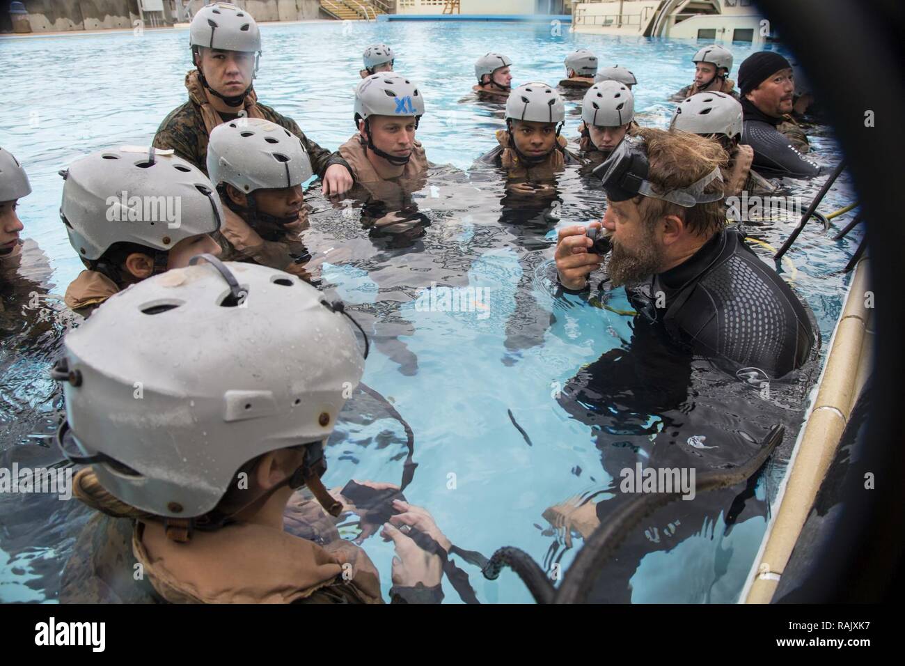 Jason Comeaux, Underwater Egress Training instructor, right, demonstrates how to breathe through an air regulator during UET on Camp Hansen, Okinawa, Japan, Feb. 9, 2017. U.S. Marines with Truck Company, Headquarters Battalion, 3rd Marine Division, III Marine Expeditionary Force, are required to complete UET as part of their pre-deployment training for Fuji Viper 17-3. Stock Photo