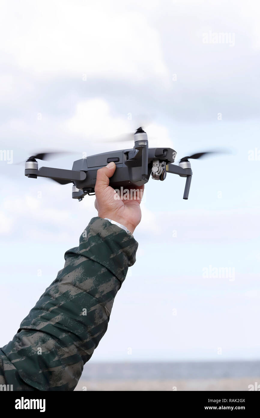 Hand catching drone aircraft in sky background, camera operator concept Stock Photo
