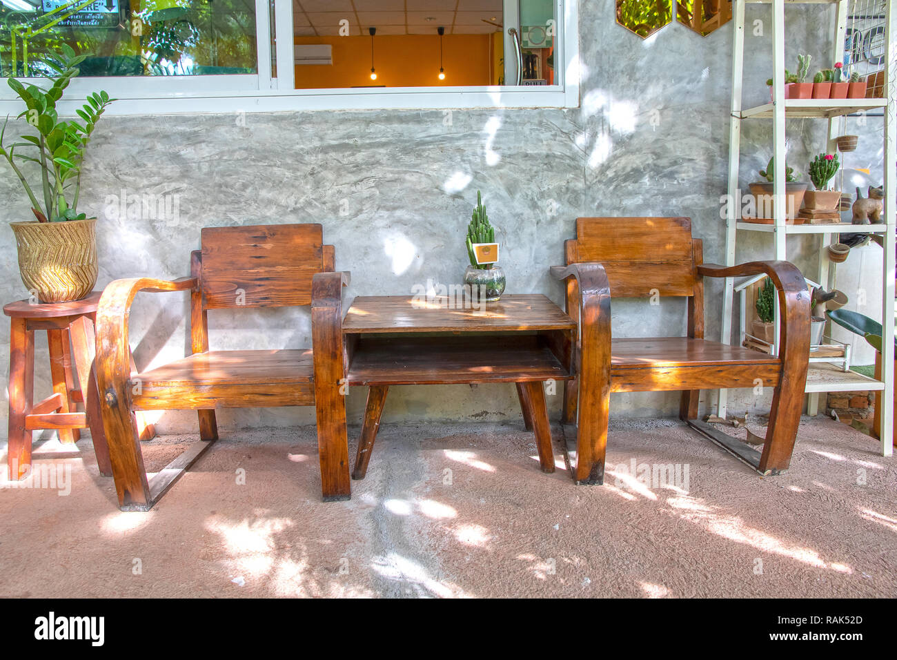 Two vintage wooden chairs on cement porch and polished cement wall front of house. Stock Photo