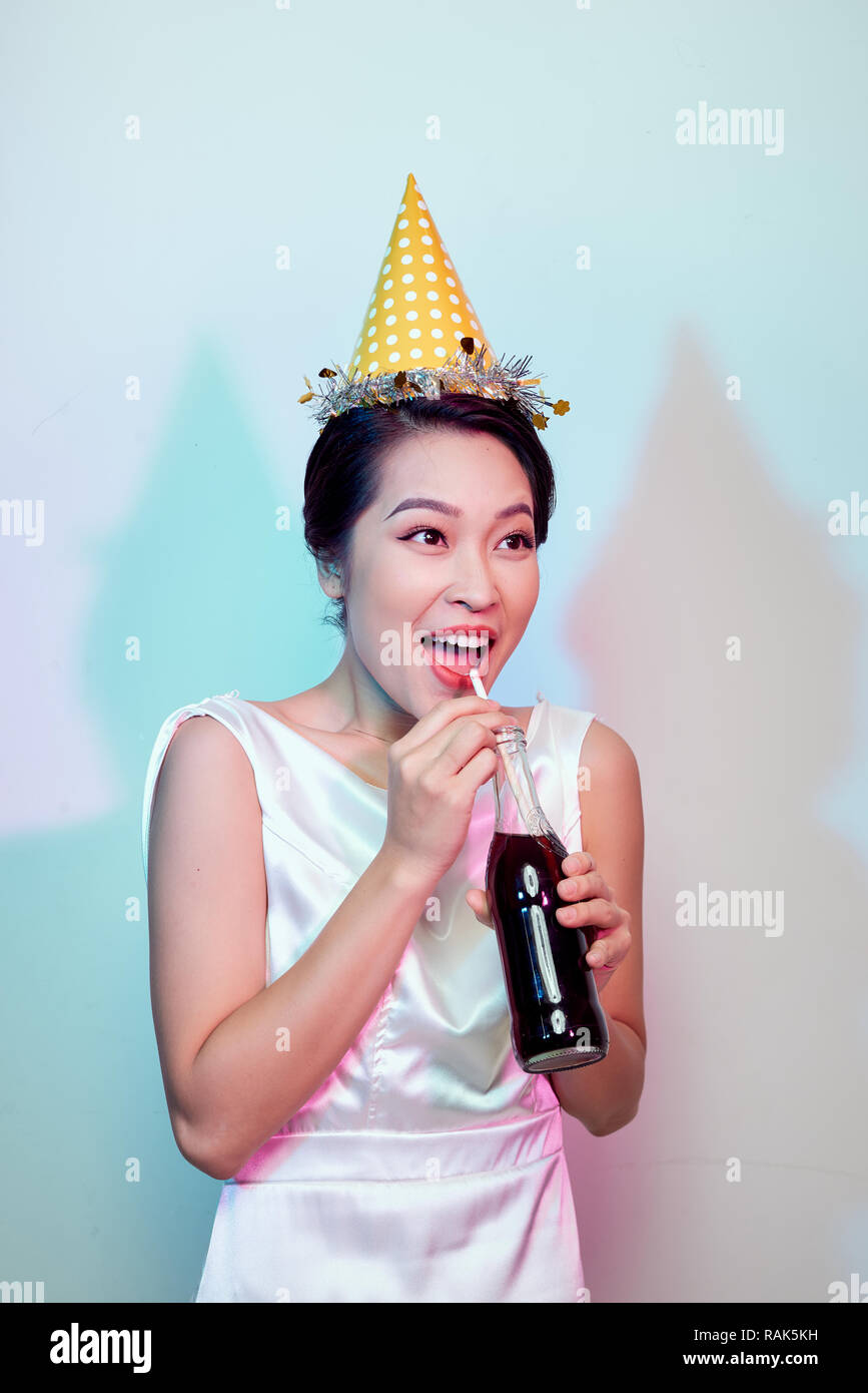 Portrait of beautiful happy cute asian woman in casual dress isolated on white, drinking cola from bottle with straw Stock Photo