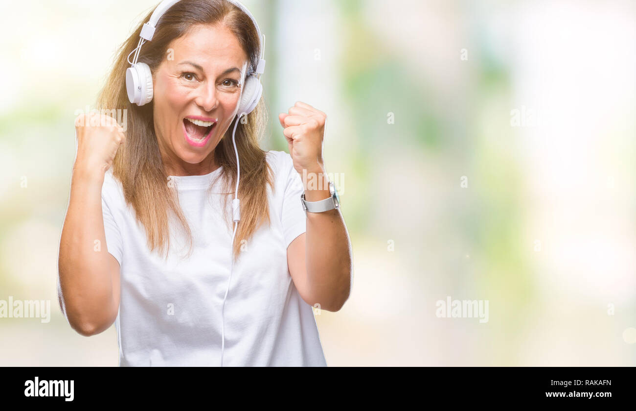 Middle age hispanic woman listening to music wearing headphones over ...