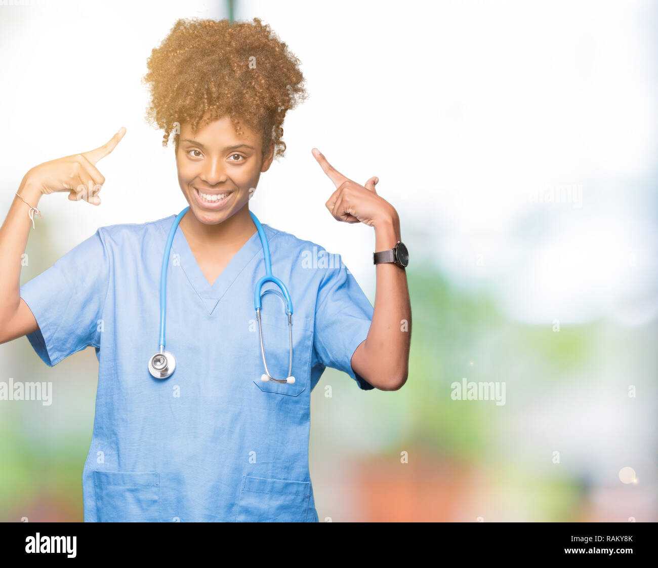Young african american doctor woman over isolated background Smiling pointing to head with both hands finger, great idea or thought, good memory Stock Photo