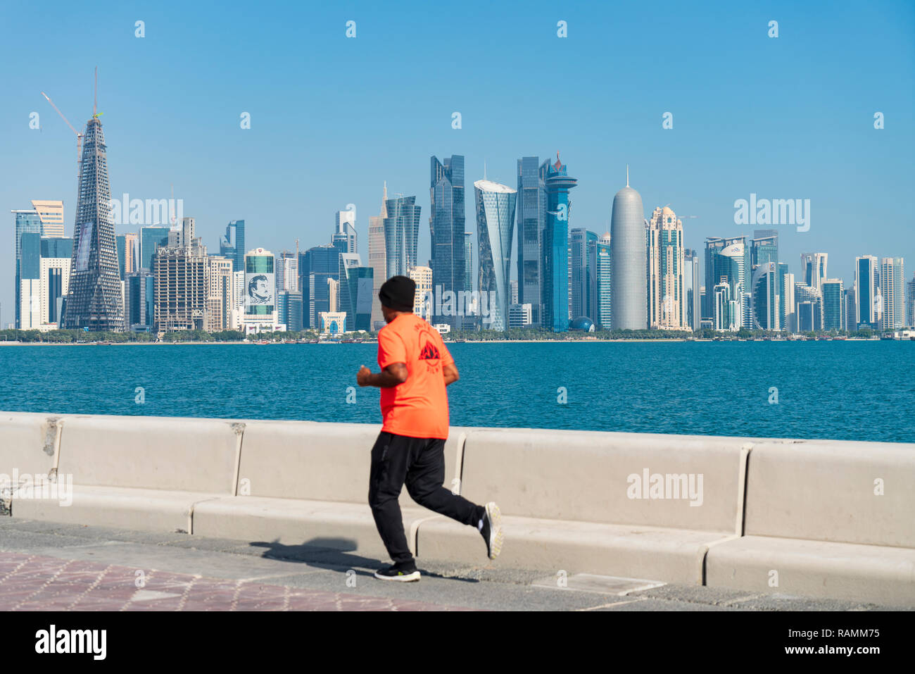 Man jogging in front of Skyline view of West Bay business district from The Corniche in Doha, Qatar Stock Photo