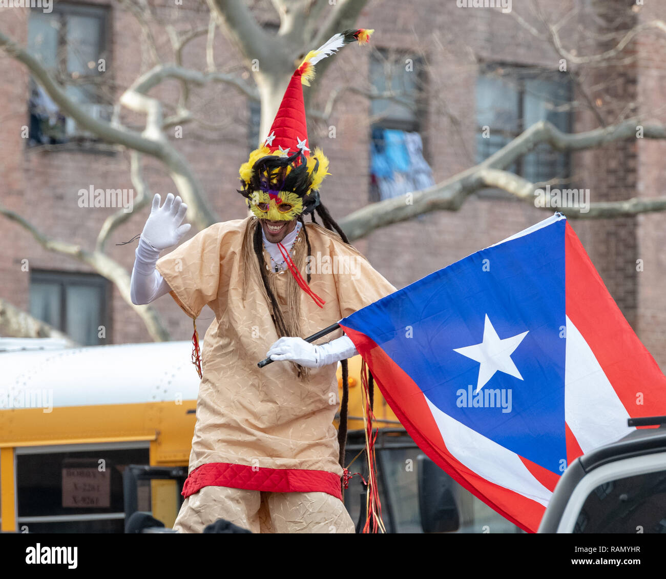 New York, USA. 4th Jan 2019. A performer on stilts waves a flag of Puerto Rico as he greets the public during the 42nd Annual Three Kings Day Parade El Barrio (East Harlem, New York city), Organized by El Museo del Barrio, the event celebrates the popular belief that three wise men visited Jesus. Credit: Enrique Shore/Alamy Live News Stock Photo