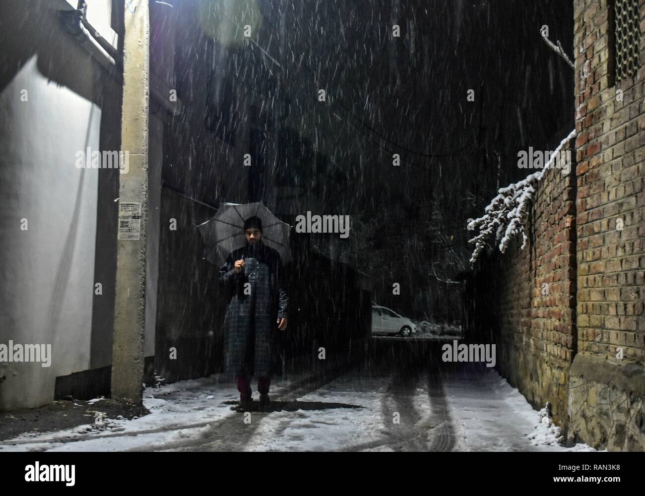 A resident seen walking through a snow covered street during snowfall. Kashmir received its first snowfall of the new year, breaking a month-long dry spell in the Valley. Srinagar recorded a 0 degrees Celsius -- an increase of over four degrees from minus 4.2 degrees Celsius on the previous, the Met department said. The weather department has predicted more snowfall in Kashmir over the next three days. Stock Photo