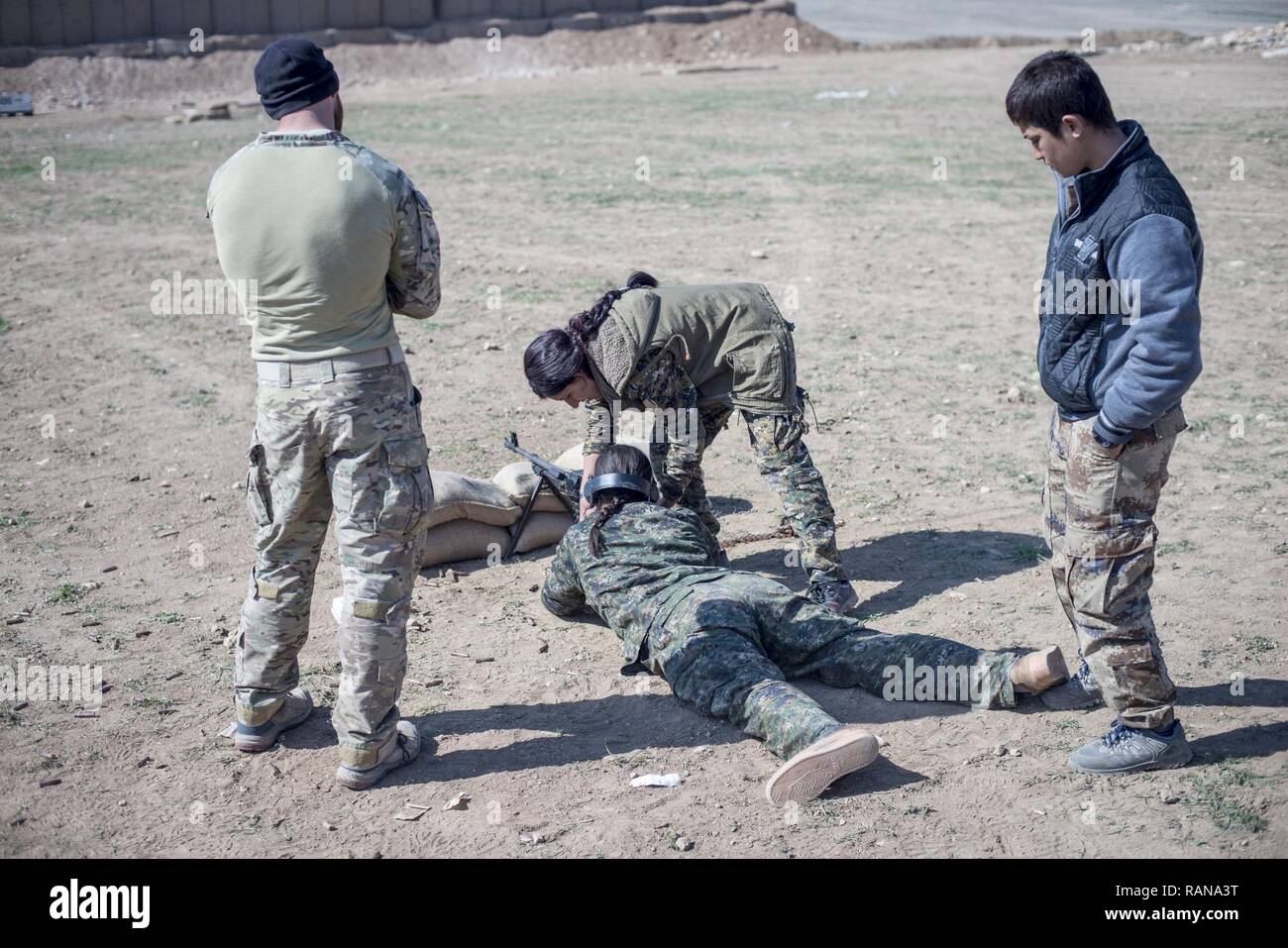 A U.S. Special Forces operator advises a Manbij Military Council female instructor as she helps a local female MMC trainee during marksmanship training Feb. 21, 2017, at Sanaa Training Center in Northwest Syria. This is the first cycle of women to graduate and join the MMC. The MMC is a multi-ethnic force that includes Kurds, Arabs, Christians, Turkmen, Yazidis and others. The course is administered by Special Operations Joint Task Force – Operation Inherent Resolve trainers. Stock Photo