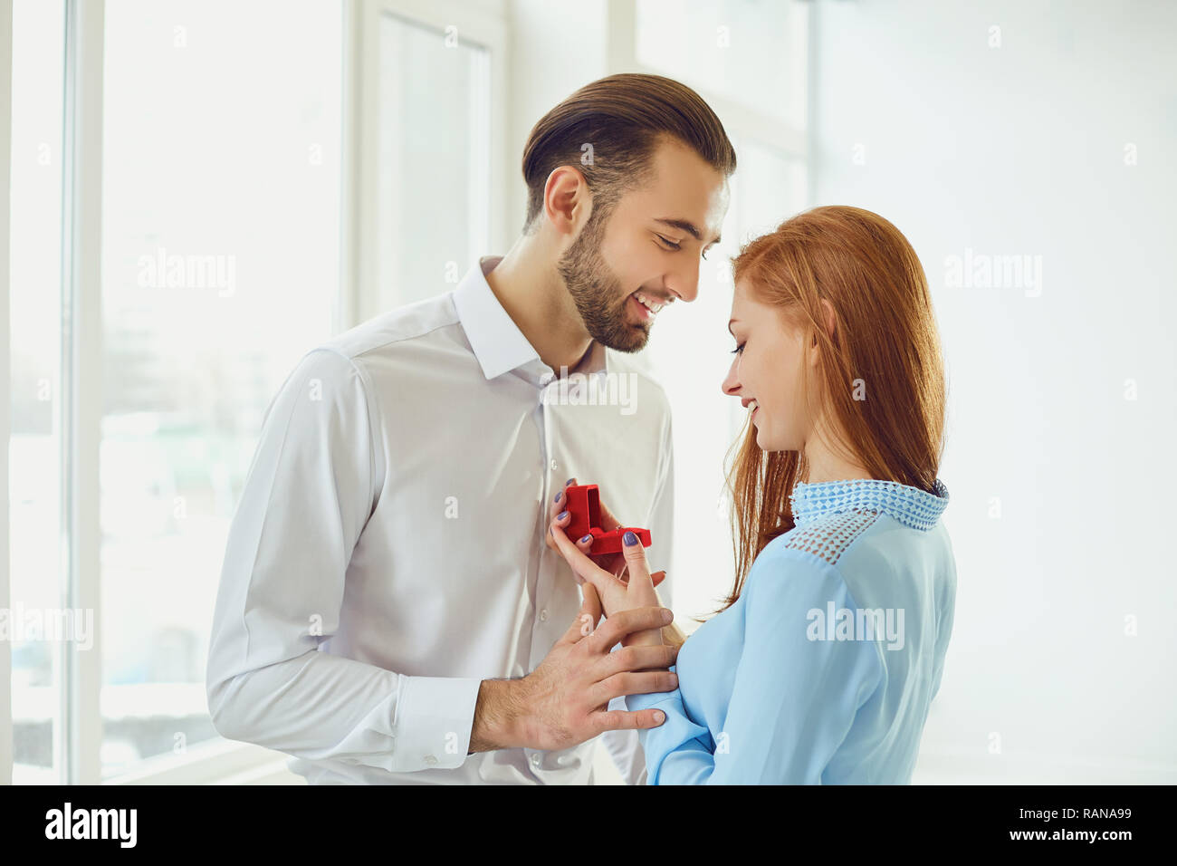 Man proposes to a girl in room with bright windows. Stock Photo