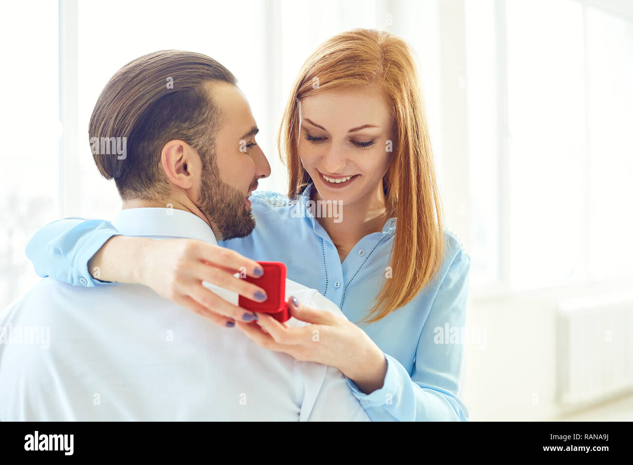 Man proposes to a girl in room with bright windows. Stock Photo