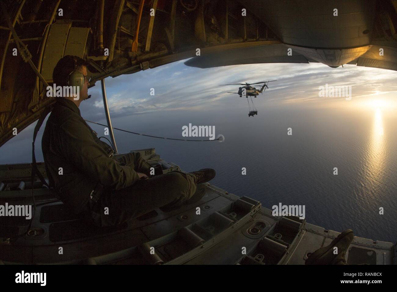 U.S. Marine Corps Cpl. Juan Sierra, a crew master assigned to Marine Aerial Refueler Transport Squadron (VMGR) 234, observes an aerial refuel training operation from the back of a KC-130J Hercules on Feb. 23, 2017. VMGR-234 assisted Marine Heavy Helicopter Squadron 464 in the training to maintain interoperability. Stock Photo