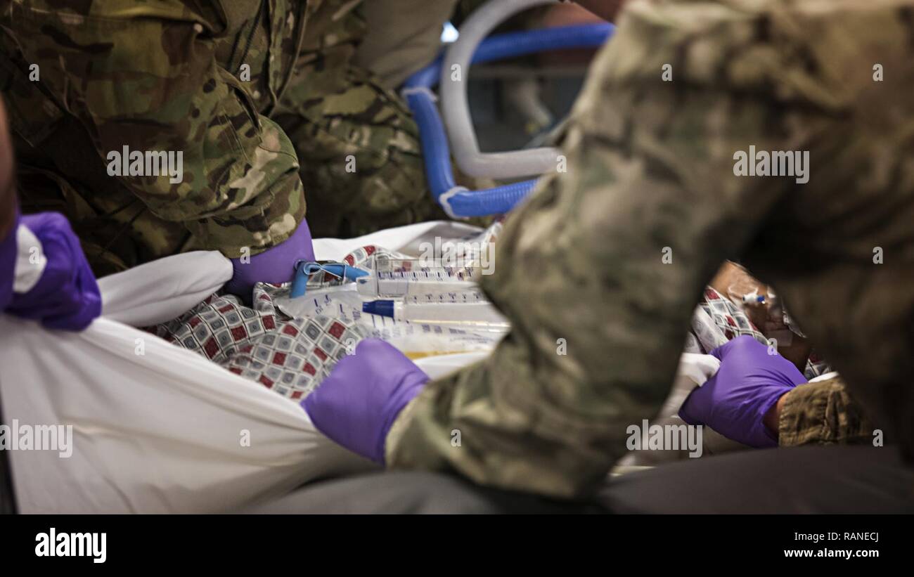 Members of the 455th Expeditionary Aeromedical Evacuation Squadron Critical Care Air Transport Team move a patient onto a litter at the Kandahar Regional Military Hospital, Kandahar Airfield, Afghanistan Feb. 22, 2017. CCATTs are made up of a doctor, a nurse and a respiratory therapist who provide in-flight medical care to critically injured or ill patients. Stock Photo
