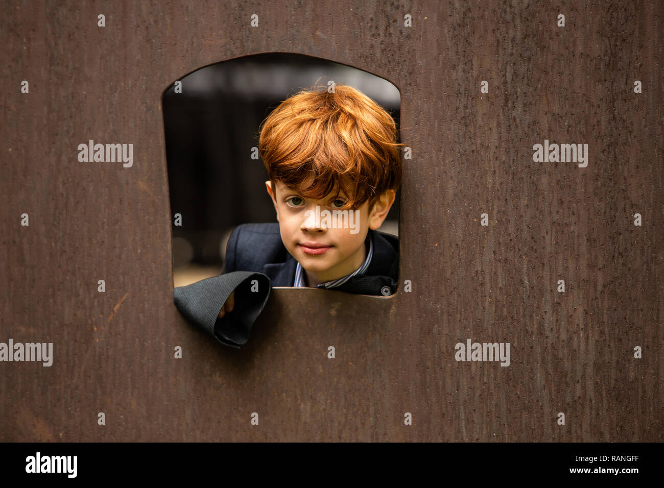 Close up of Red headed boy looking out window outside Stock Photo