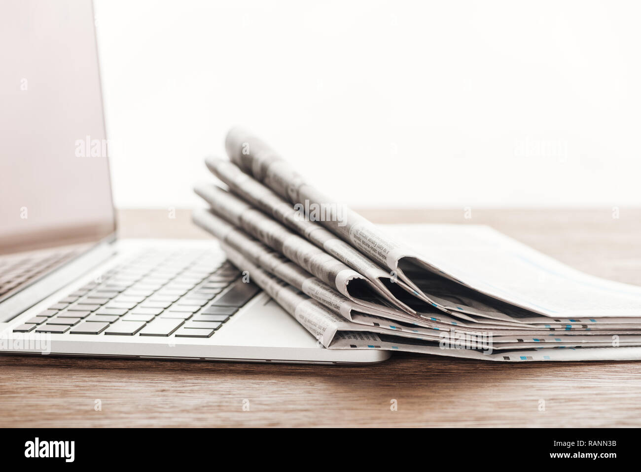laptop and stack of newspapers on wooden tabletop Stock Photo Alamy