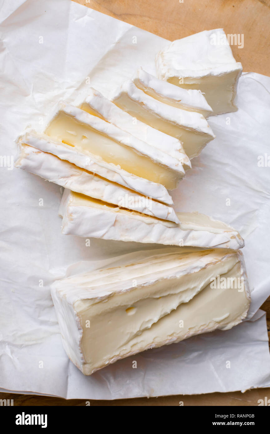 close up of sliced soft white rind cheese on wooden cutting board Stock Photo