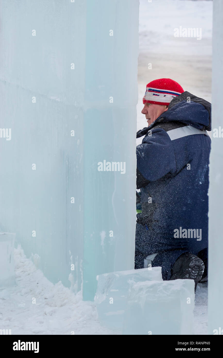The sculptor cuts an ice figure for Christmas from a block of ice with ...